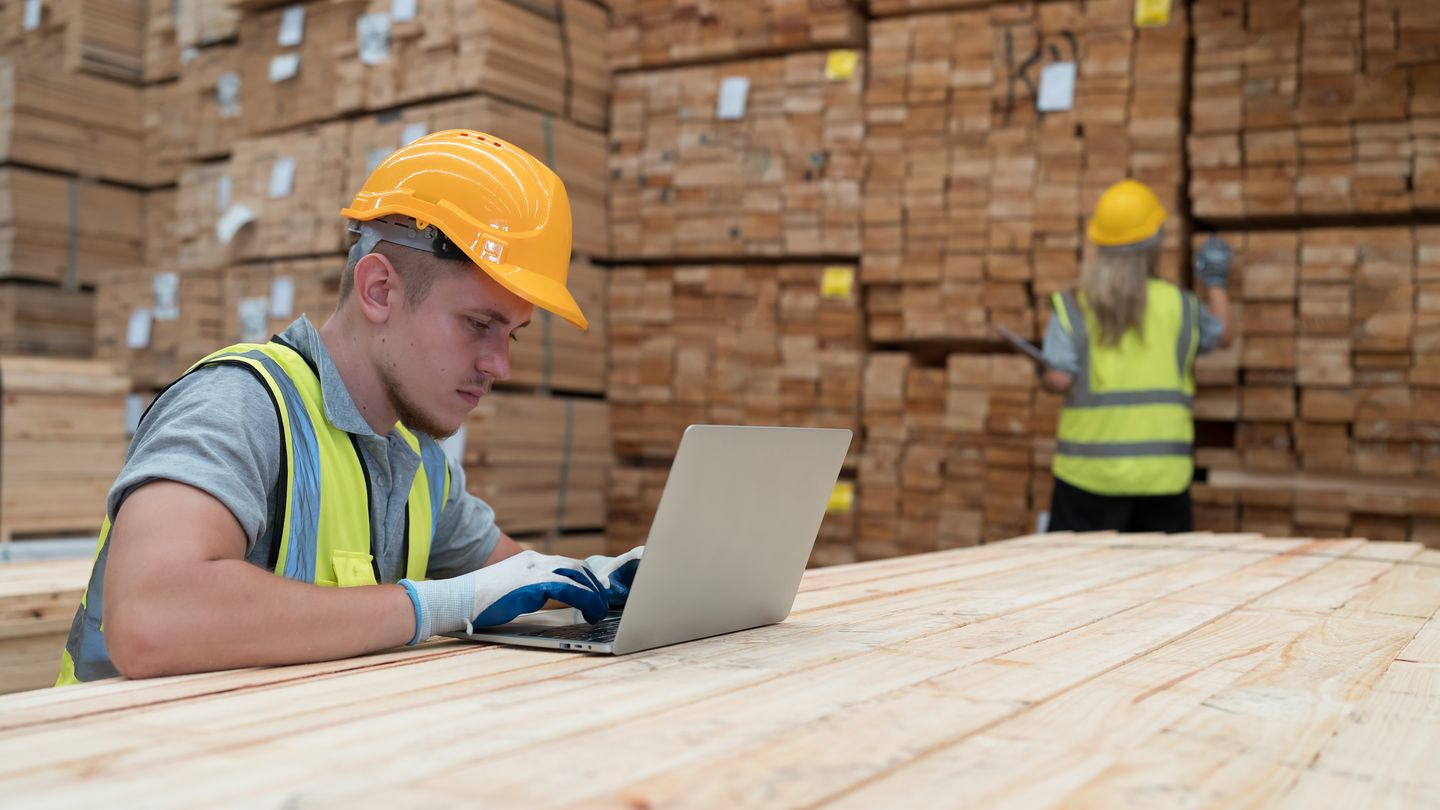 Mitarbeiter prüft Unterlagen am Laptop im Lager