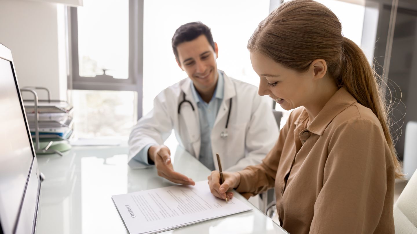 Ärztin im Gespräch mit einer Patientin am Schreibtisch einer Praxis