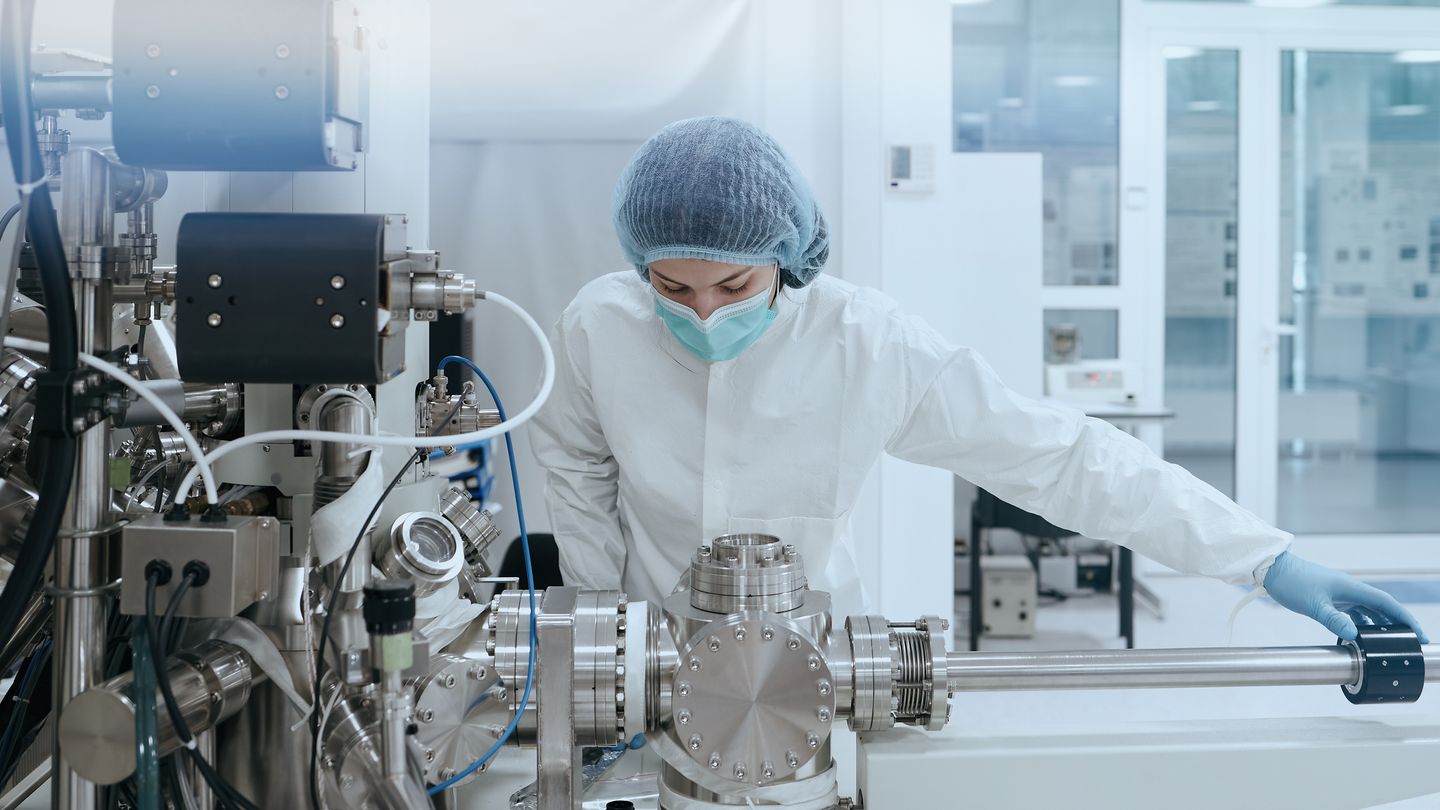 Mitarbeiterin in Schutzkleidung an einer Anlage in der chemischen Industrie