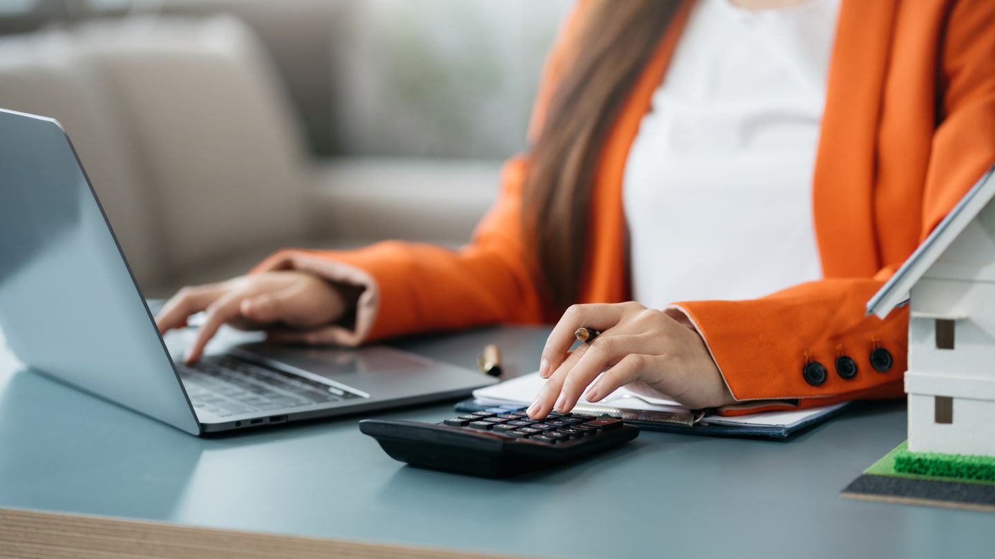 Beraterin am Laptop mit Taschenrechner und Auswertung