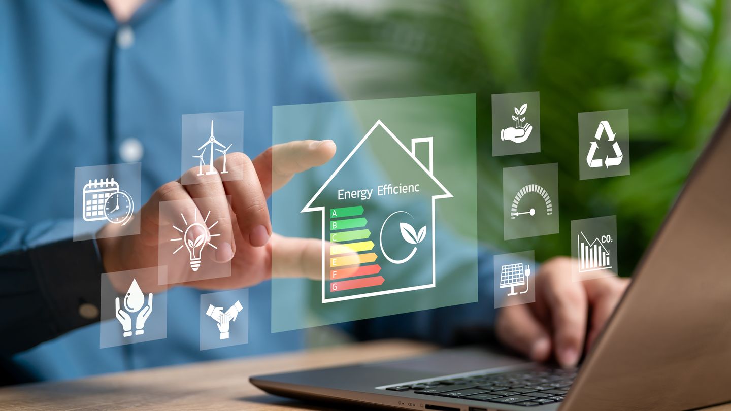 Person am Laptop, daneben eingeblendete Symbole rund um Energie im Gebäude